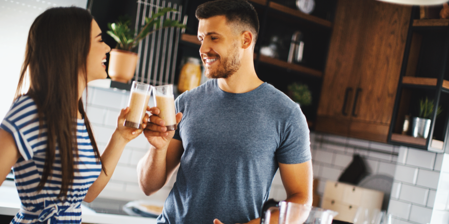 Man and woman in kitchen drinking smoothies