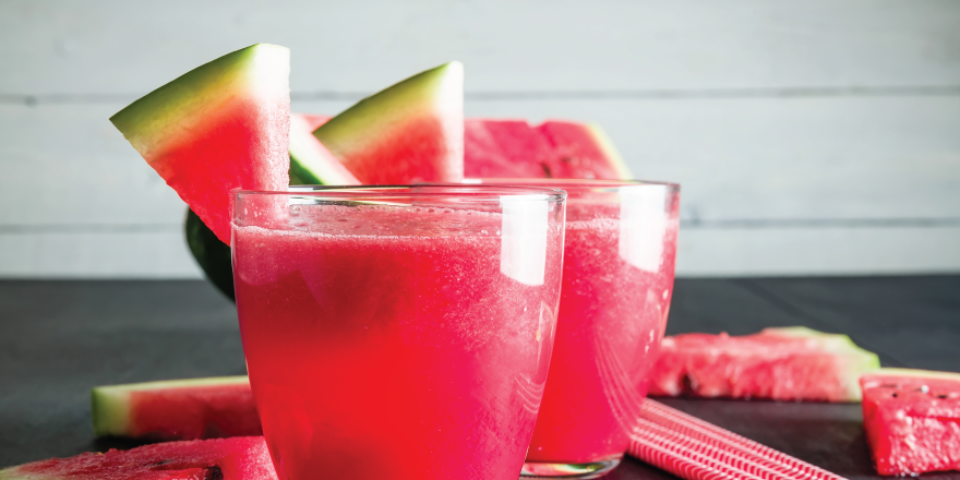 Watermelon slush in clear glass with watermelon wedge on the rim