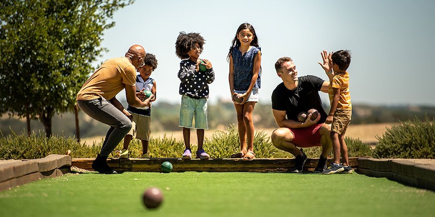 Family playing bocce on court