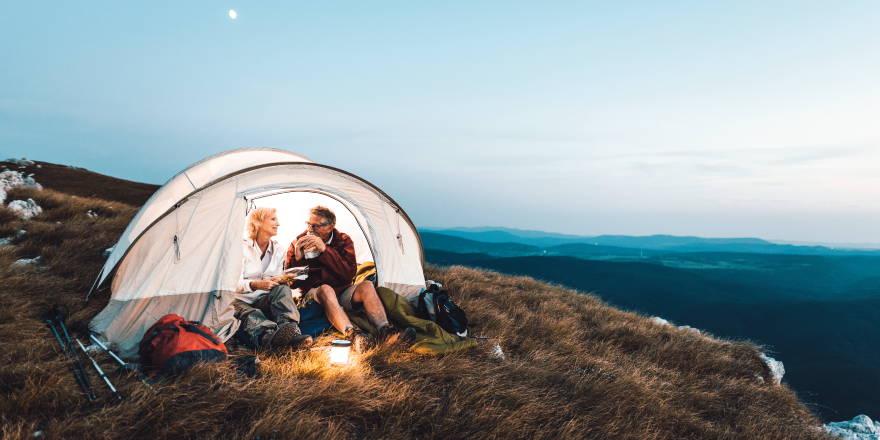 people in tent outside by campfire